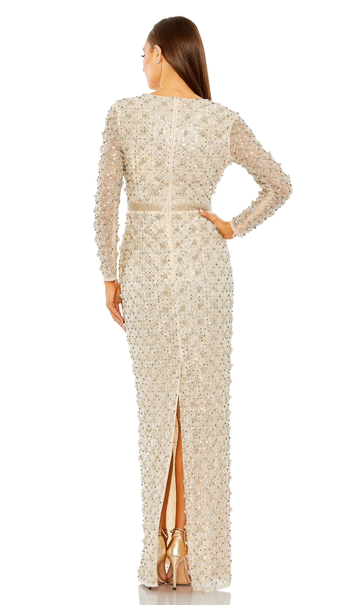 A woman faces away from the camera, wearing the Long Formal Dress 93827 by Mac Duggal—a beige, floor-length gown with long sleeves, delicate beading, a back slit, and paired with gold heels.